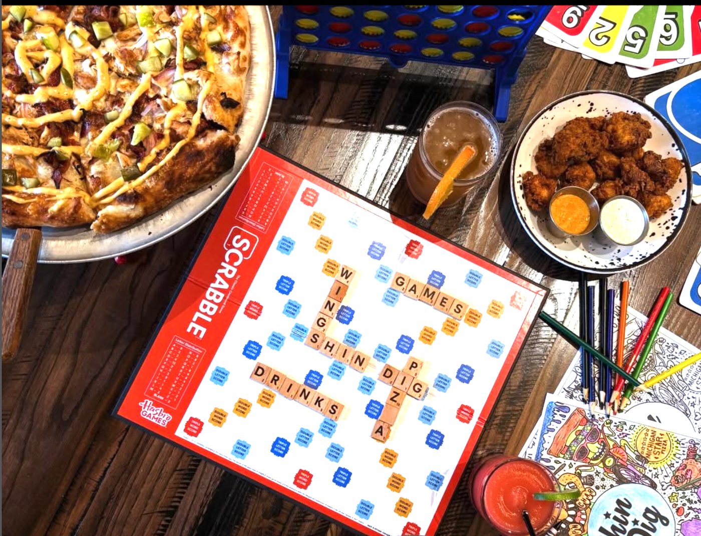 Shin Dig Patio Party games table with food, drinks and branded Scrabble board